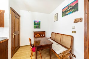 Une pièce comprenant une table à manger en bois, un canapé, une porte et un mur orné d’un tableau.