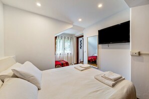 Ein Hotelzimmer mit Bett, Wandfernseher und einem Vorhangfenster.