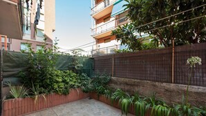A courtyard with a tiled floor, a wooden fence, and various plants. - Apartment 'Casa Sestri Ponente' with Shared Garden, Wi-Fi and Air Conditioning (Genova)