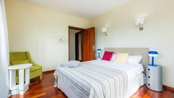 Ein Hotelzimmer mit Bett, Nachttischen, einem Sessel und einer Tür.