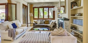 A living room with a sofa, armchairs, a coffee table, a fireplace, and a bookshelf. - Seaside Luxury Villa with Saltwater Pool in Palma de Mallorca (Can Pastilla)
