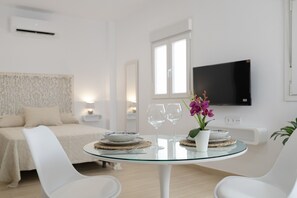A modern hotel room with a bed, a round glass table with two chairs, a TV, and a window. - Studio Apartment 'Apartamentos Maria' with Wi-Fi and Air Conditioning (Vejer de la Frontera)