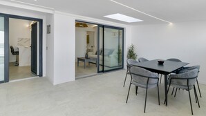 Un interior moderno con comedor, sofá y puerta de vidrio que da a otra habitación.