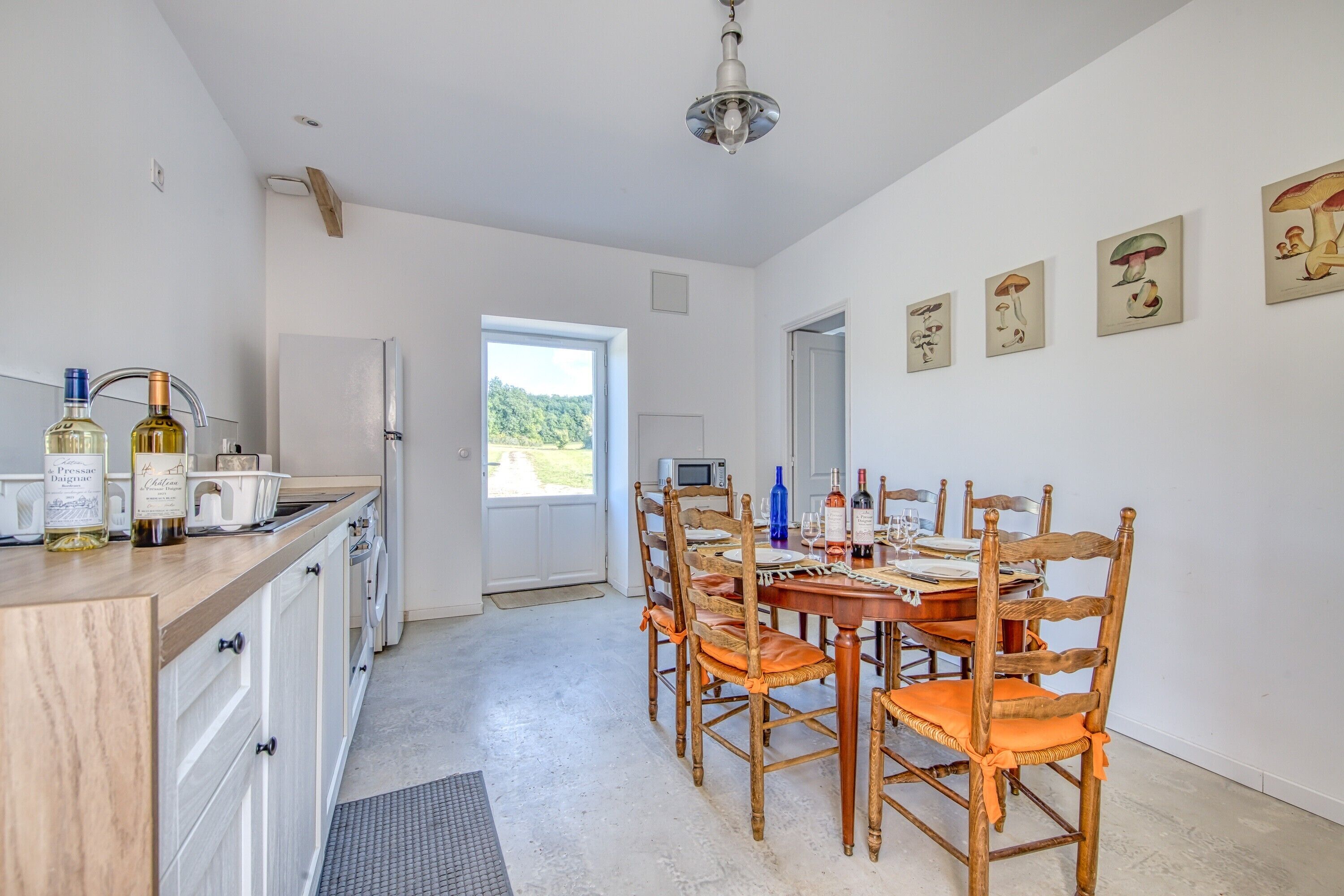 Een keuken met een eethoek, houten stoelen, een eettafel en een koelkast.