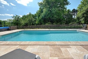 A rectangular swimming pool with a wooden deck and a lattice fence in the background.