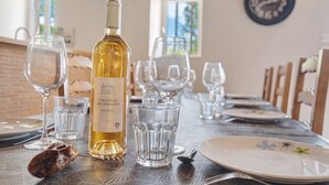 A dining table set with wine glasses, a bottle of wine, and plates. - Stone House with Private Pool and Garden – Charm & Comfort in Dordogne (La Chapelle-Gonaguet)
