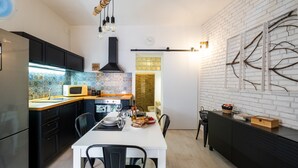 Une cuisine moderne avec des meubles noirs, un plan de travail blanc et un coin repas comprenant une table et des chaises blanches.