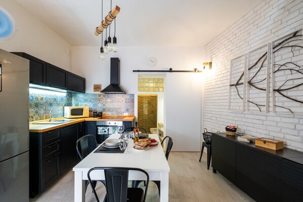 A modern kitchen with black cabinets, a white countertop, and a dining area with a white table and chairs.