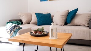 Un salon moderne avec un canapé, des coussins, une table basse et une œuvre d’art murale.