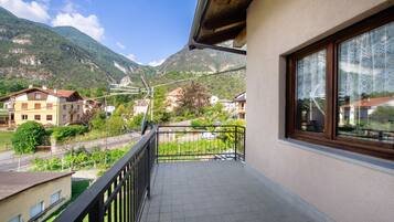 A balcony with a view of a mountain, a street, and neighboring buildings.