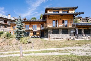 A multi-story wooden lodge with balconies, stone accents, and outdoor seating.