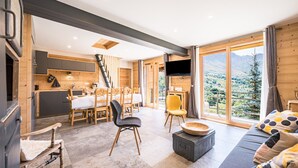 Ein modernes Interieur mit Essbereich, Küche und großem Fenster mit Blick auf die Berge.
