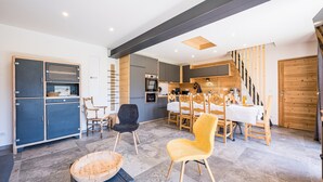 Eine moderne Küche mit Essbereich, Holzschränken und einer Treppe.