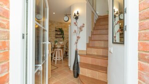 Un escalier avec des marches en bois, une horloge murale et un vase rempli de fleurs.