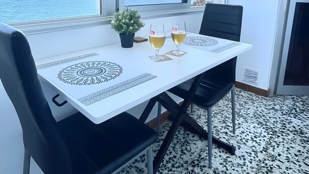 A dining area with a table, chairs, and a view of the sea.