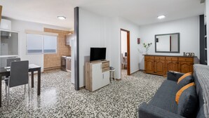 A modern living room with a sofa, TV, and dining area.