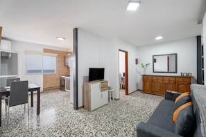 Un salon moderne avec un canapé, un téléviseur et un coin repas.