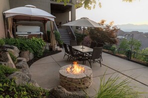 A patio with a stone fire pit, outdoor furniture, and umbrellas. - New! Paragliding Paradise | Hot Tub | Grill | View (Draper)