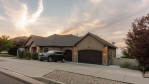 Une maison d’habitation avec un garage, une allée et un VUS garé.