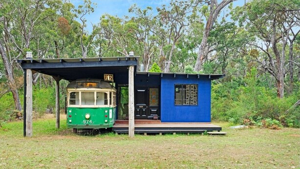 A green tram with the number 974 parked under a shelter, adjacent to a small blue building with a window. - Seclusion, Tram, Native Bush, Wineries, Beaches, Melbourne Icon, Village nearby (Balnarring)