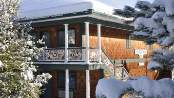 A two-story building with a wooden facade and a balcony with intricate white railings.