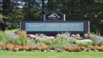 A sign for Shanty Creek Resorts with a logo, name, and location details.