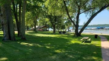 A park with picnic tables, a gazebo, and a lake view.