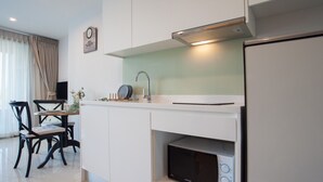Une cuisine moderne avec des armoires blanches, un four à micro-ondes encastré et un coin repas comprenant une table et des chaises.