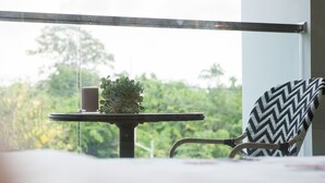 Un balcon avec une table, un pot de fleurs et une chaise.