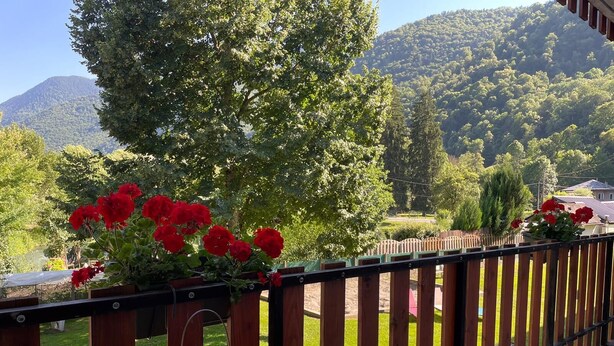 A balcony with a view of a mountainous landscape, a wooden fence, and a table with chairs. - Pyrenees Panorama - Garonne River Apartment with Balcony (Saint-Beat-Lez)