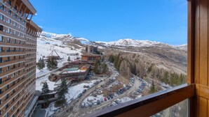 Un hôtel avec vue sur une chaîne de montagnes enneigées et un parking.