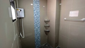 A small, modern shower area with a glass door, a tiled wall, and a metal towel rack.