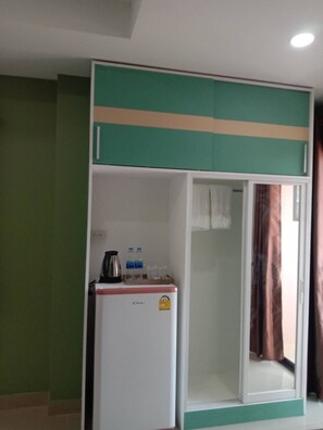 A room with a white refrigerator, a green and beige cabinet, and a brown curtain. - W-town Apartments  (Phetchaburi)