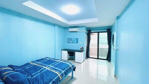 A bedroom with a bed, a desk, and a balcony.