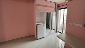A room with pink walls, a white refrigerator, a sliding door, and a wooden table.