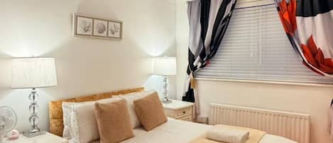 Een netjes ingerichte slaapkamer met een bed, nachtkastjes, een lamp en een raam met gordijnen.