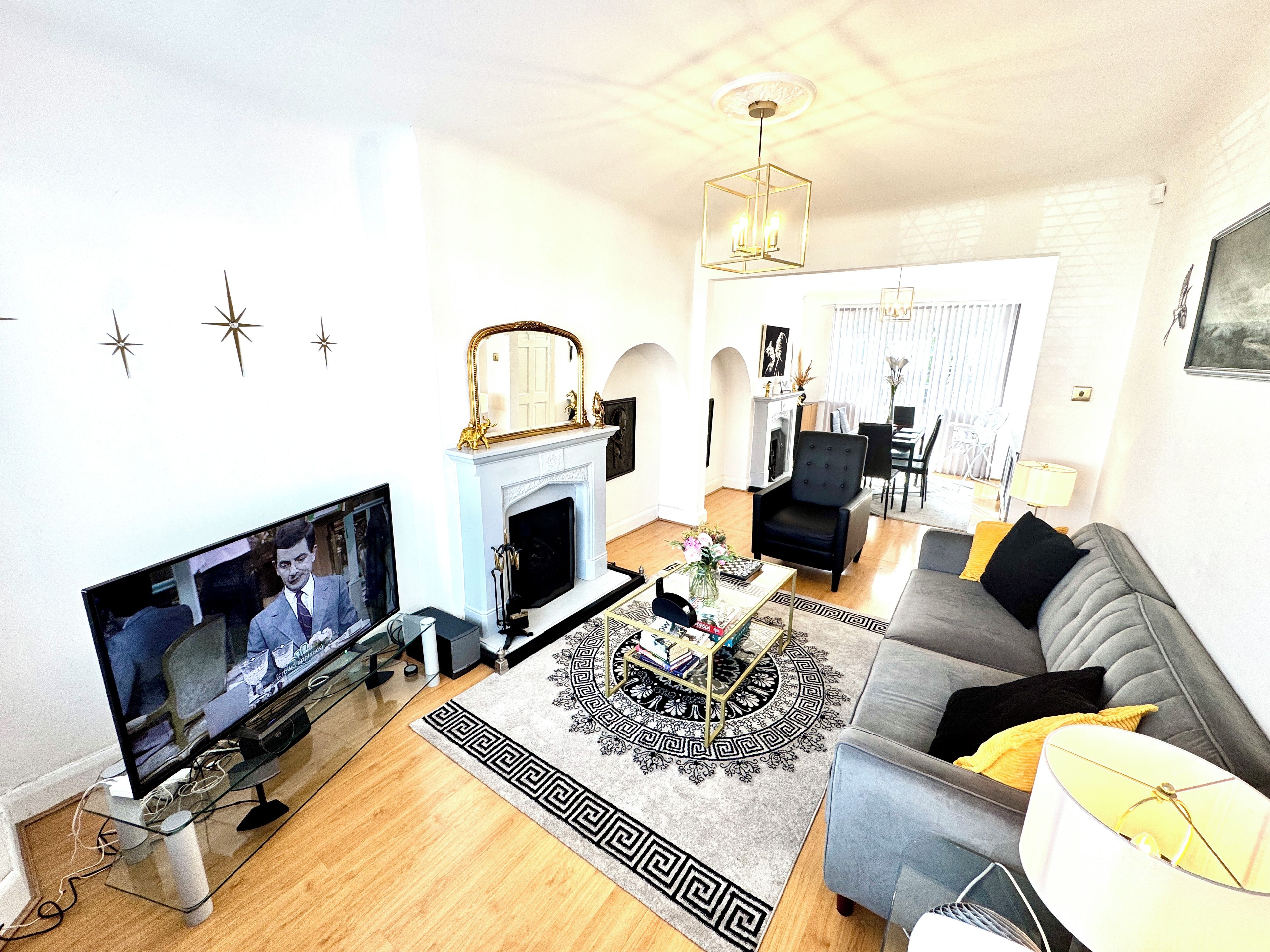 A living room with a television, fireplace, sofa, and a dining area in the background.