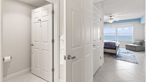 Un dormitorio con cama, vista al océano, ventilador de techo y ventana.