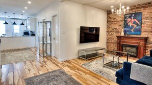 A modern living room with a fireplace, a television, and a dining area in the background.