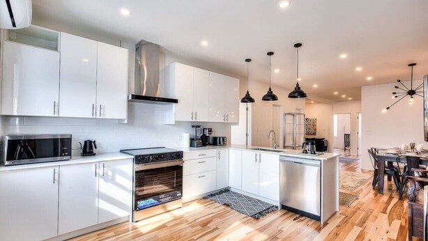A modern kitchen with white cabinets, a central island, and pendant lighting.
