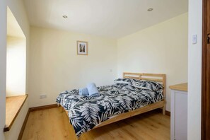 A single bed with a leaf-patterned bedspread in a room with wooden flooring and a white wall. - Beautiful Cottage in Idyllic Cotswolds Village (Chalford Hill)