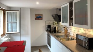 Une cuisine moderne avec des meubles blancs, un évier en acier inoxydable et un four encastré.