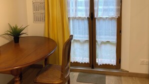 Un coin repas avec une table et des chaises en bois, une plante en pot et un calendrier accroché au mur.