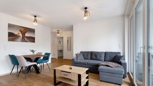 A modern living room with a sofa, a dining table with chairs, and a coffee table.