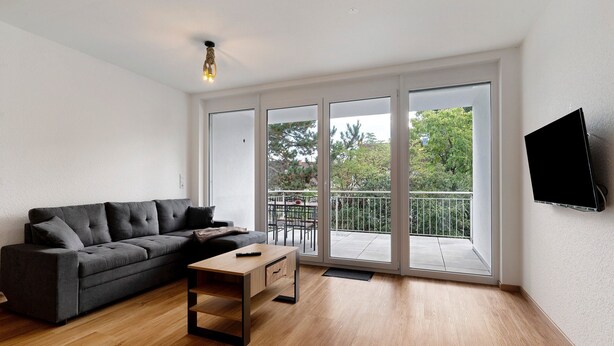 A modern living room with a sofa, a coffee table, and a TV mounted on the wall.