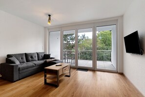 A modern living room with a sofa, a coffee table, and a TV mounted on the wall. - Apartment '2' with Balcony and Wi-Fi (Kappel-Grafenhausen)