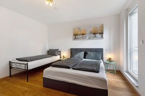 A bedroom with a large bed, a smaller bed, a nightstand, a painting, and a window. - Apartment '2' with Balcony and Wi-Fi (Kappel-Grafenhausen)