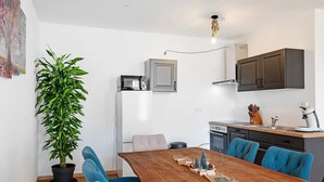 Una cocina moderna con comedor, una planta en maceta y una mesa de madera.