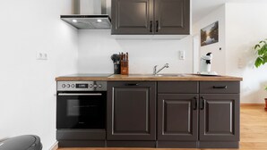 Una cocina moderna con armarios oscuros, horno empotrado y encimera de madera.