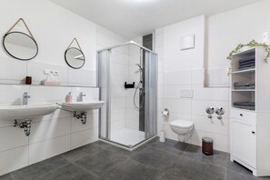 Ein modernes Badezimmer mit zwei Waschbecken, einer Dusche, einer Toilette und einem Schrank.